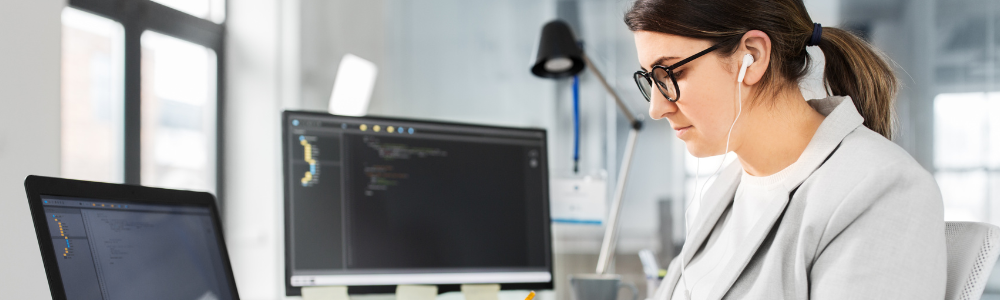 woman at desk with multiple computer screens